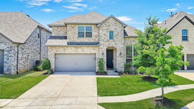 782 Corner Post Path, Celina, TX 75009 - french country home with a front yard, brick siding, an attached garage, concrete driveway, and central air condition unit