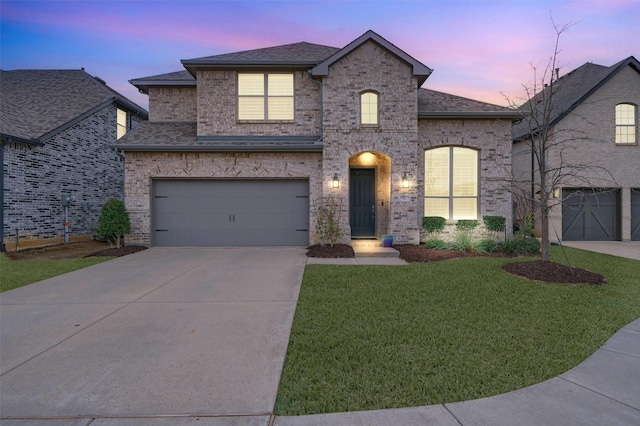 french country inspired facade with brick siding, a garage, a shingled roof, and a front lawn