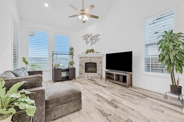 living area with wood finished floors, baseboards, lofted ceiling, a fireplace, and ceiling fan