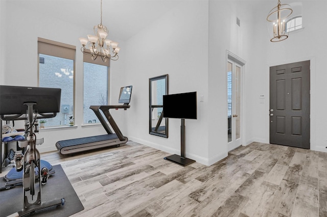 exercise room with wood finished floors, a wealth of natural light, and a chandelier