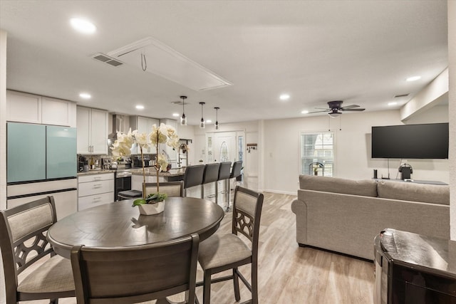 dining space featuring light wood-style flooring, recessed lighting, visible vents, a ceiling fan, and attic access