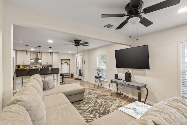 living area with light wood-type flooring, baseboards, visible vents, and recessed lighting