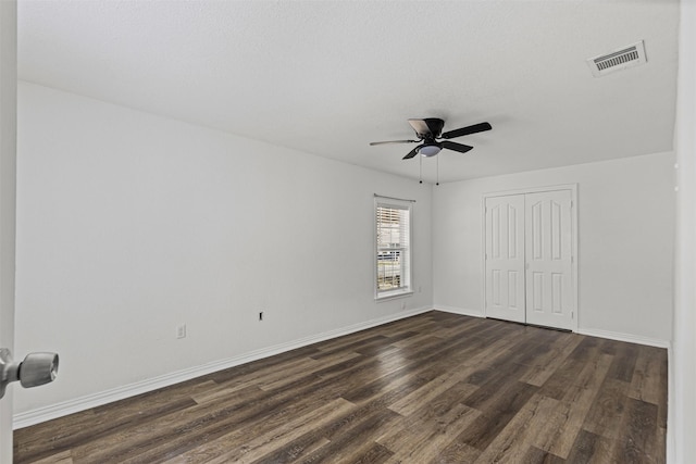 unfurnished bedroom with baseboards, visible vents, a ceiling fan, dark wood-type flooring, and a closet