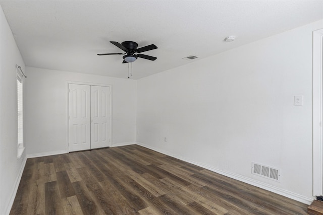 unfurnished bedroom featuring a closet, dark wood finished floors, visible vents, and baseboards