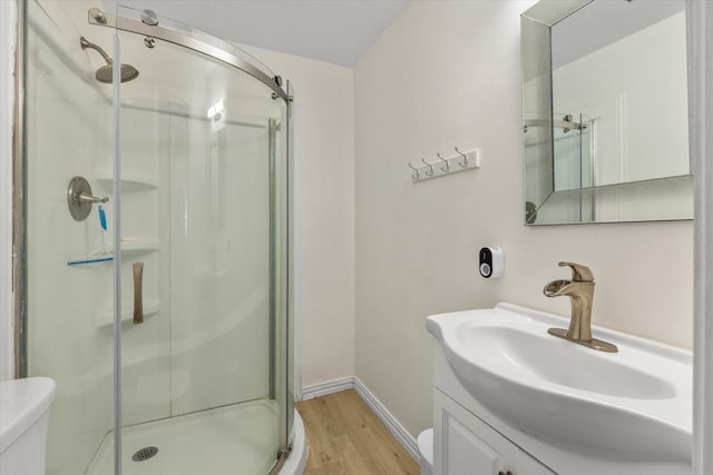 bathroom featuring toilet, a shower stall, vanity, wood finished floors, and baseboards