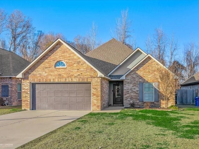 view of front facade with brick siding, a shingled roof, concrete driveway, an attached garage, and a front yard