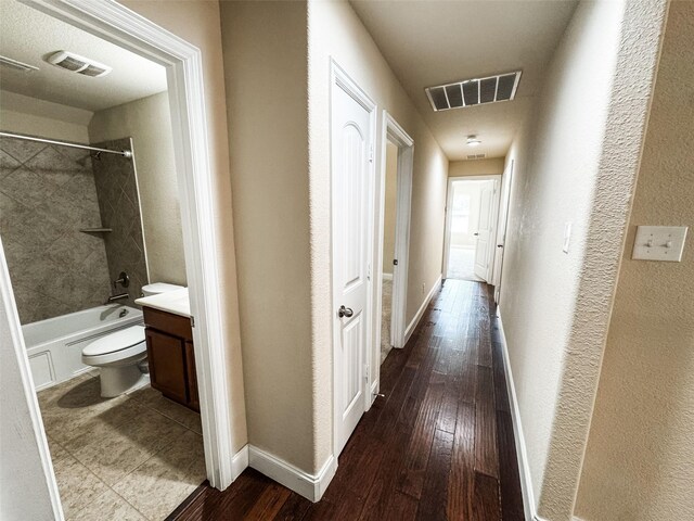 hallway with visible vents, baseboards, and wood finished floors