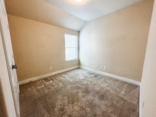 spare room with baseboards, lofted ceiling, and carpet