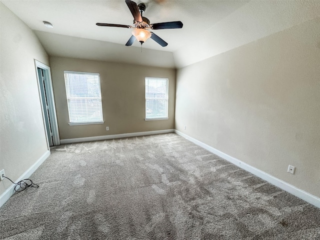 unfurnished room featuring lofted ceiling, a ceiling fan, carpet flooring, baseboards, and a textured wall