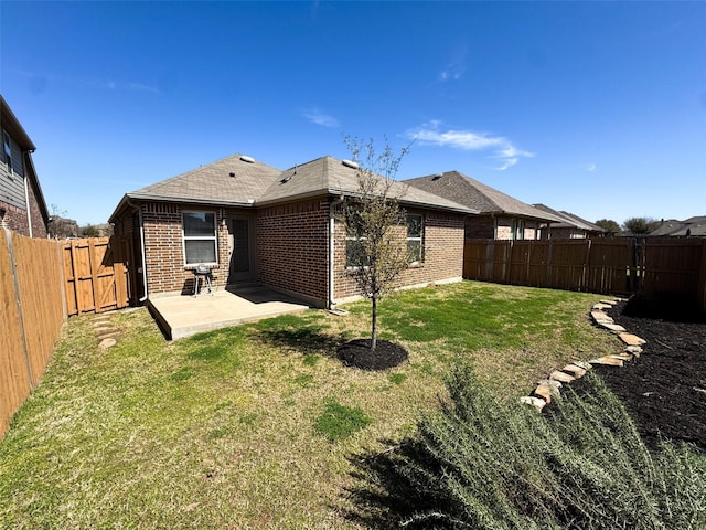 back of property with brick siding, a patio area, a lawn, and a fenced backyard