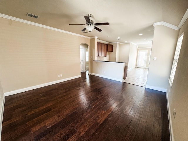 unfurnished living room with visible vents, arched walkways, dark wood-style floors, and ornamental molding