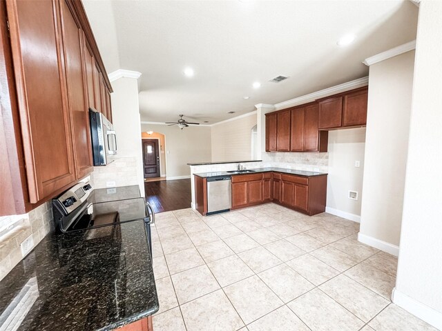 kitchen featuring brown cabinets, a sink, dark stone counters, appliances with stainless steel finishes, and crown molding