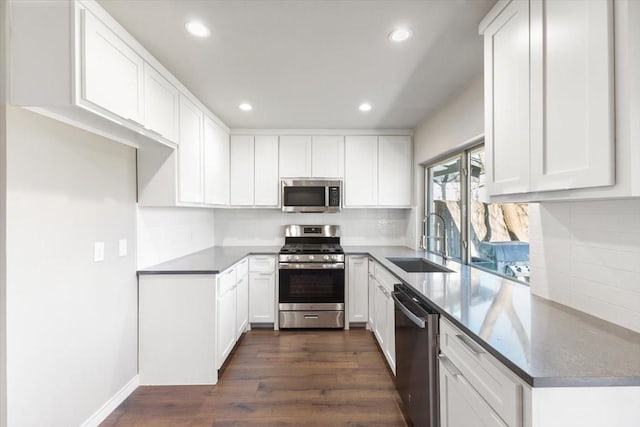 kitchen featuring dark wood-style floors, appliances with stainless steel finishes, a sink, and white cabinets