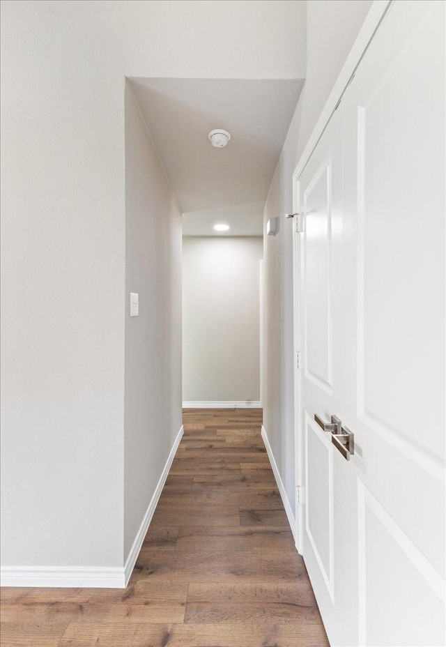 corridor with baseboards and wood finished floors