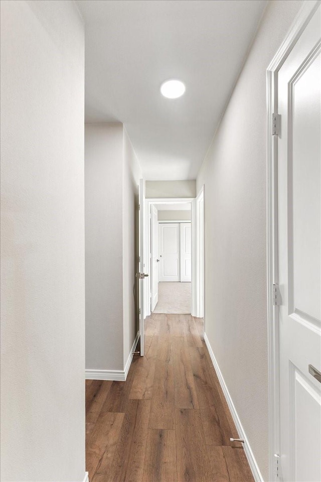 corridor featuring baseboards and wood finished floors