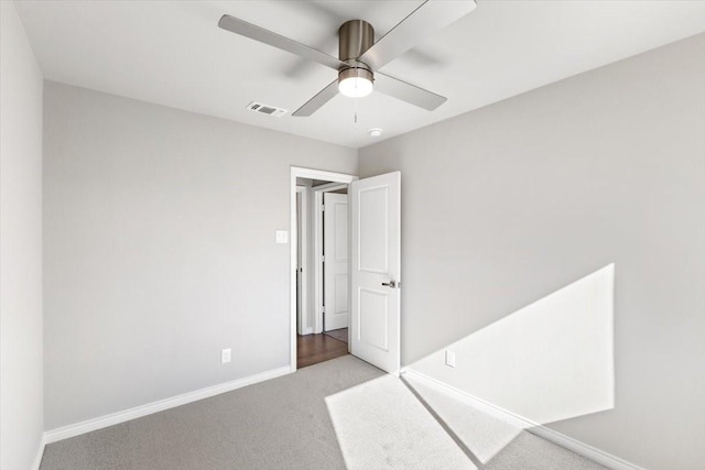 carpeted empty room with baseboards, visible vents, and ceiling fan