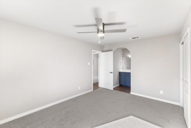 unfurnished bedroom featuring visible vents, arched walkways, baseboards, and carpet flooring