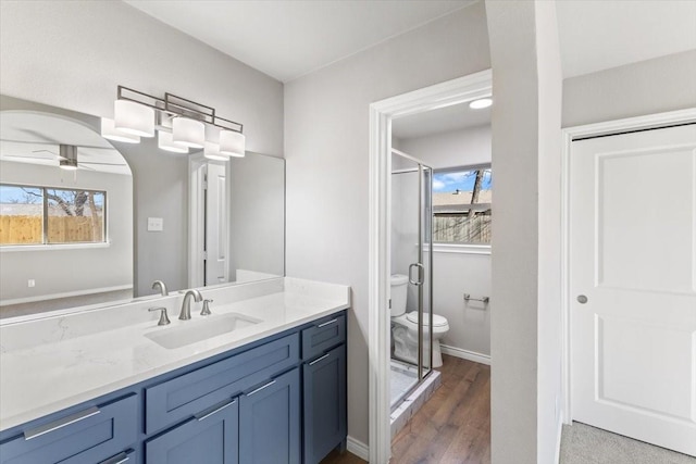 full bath featuring a stall shower, baseboards, a ceiling fan, toilet, and vanity