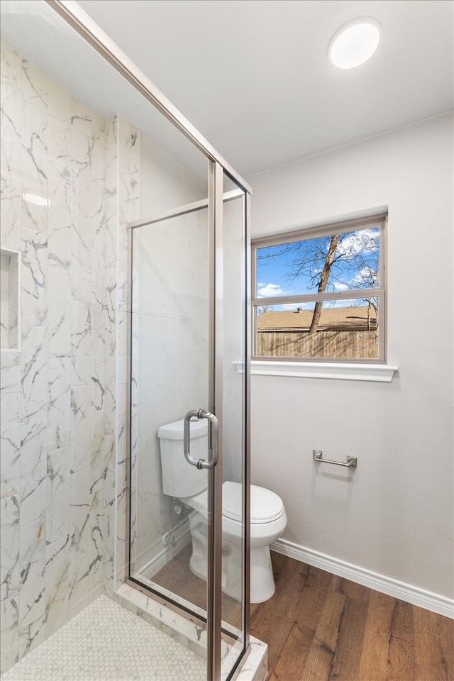 bathroom featuring a marble finish shower, baseboards, toilet, and wood finished floors