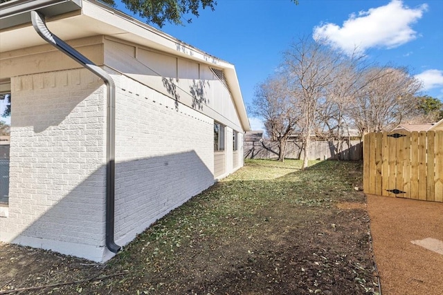 view of home's exterior featuring brick siding and fence