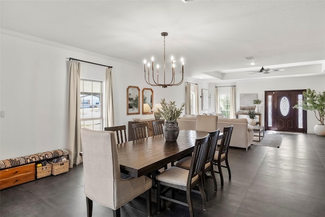 dining space with ornamental molding, a tray ceiling, visible vents, and ceiling fan with notable chandelier