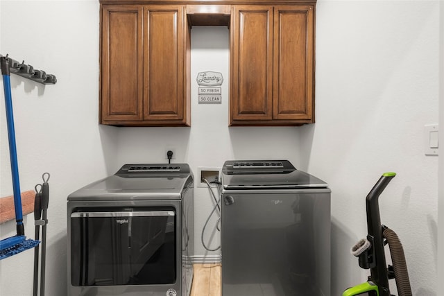washroom with cabinet space, light wood-style flooring, and independent washer and dryer