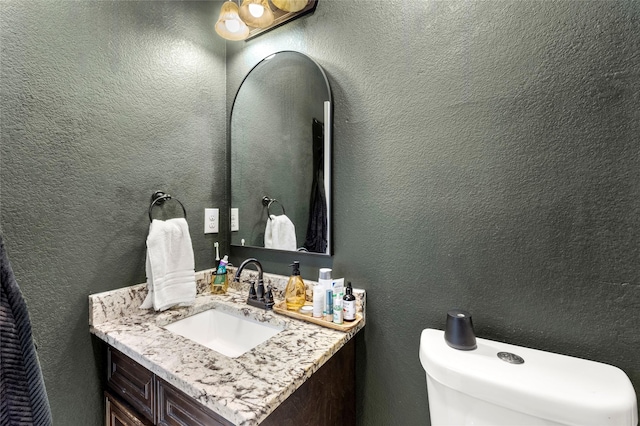 half bathroom featuring vanity and a textured wall