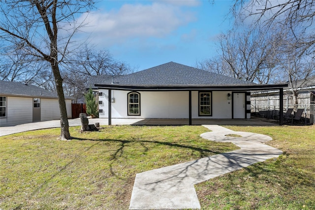 view of front of house with a shingled roof, fence, a front lawn, and stucco siding