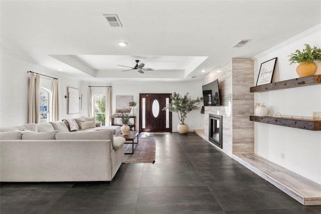 living room with a raised ceiling, visible vents, and a fireplace