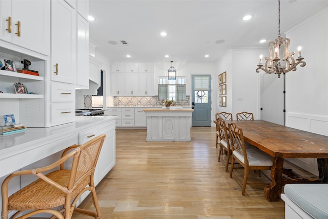 kitchen with a center island, light countertops, backsplash, ornamental molding, and white cabinets