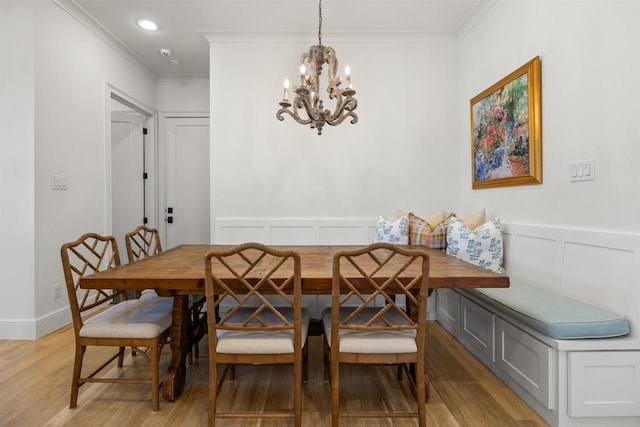 dining room with breakfast area, ornamental molding, light wood-style flooring, and a decorative wall