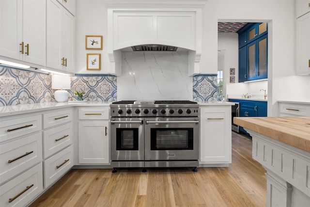 kitchen with range with two ovens, light wood-type flooring, and white cabinetry