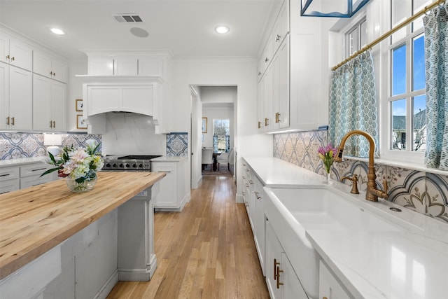 kitchen featuring white cabinetry, visible vents, wooden counters, and a sink