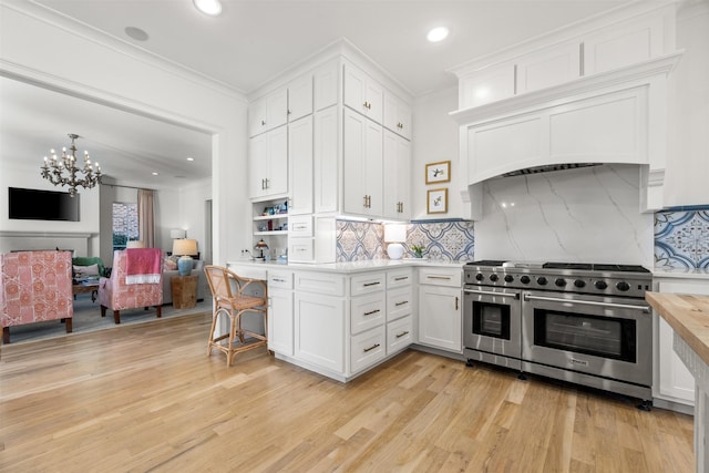 kitchen with white cabinets, range with two ovens, crown molding, and light countertops