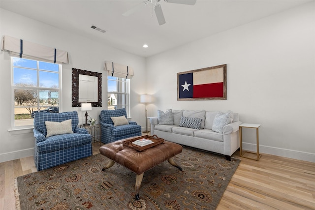 living room featuring baseboards, plenty of natural light, visible vents, and wood finished floors