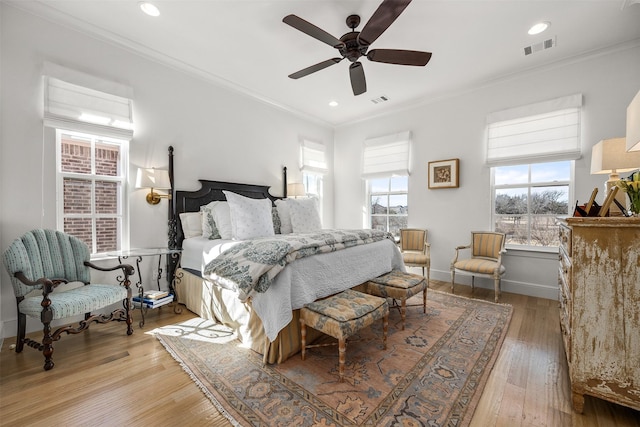 bedroom featuring light wood-style flooring, recessed lighting, visible vents, baseboards, and ornamental molding