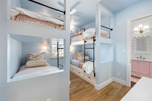 bedroom featuring baseboards, a sink, visible vents, and light wood-style floors