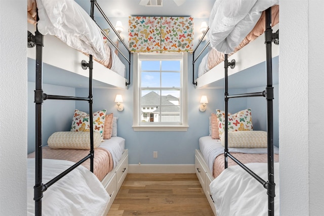 bedroom with visible vents, baseboards, and wood finished floors