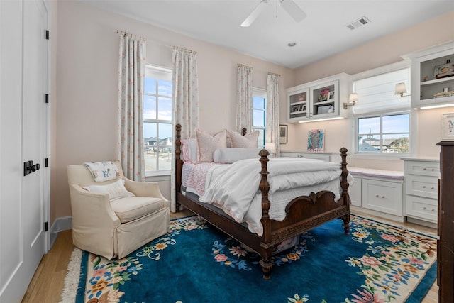 bedroom with a ceiling fan, visible vents, and wood finished floors