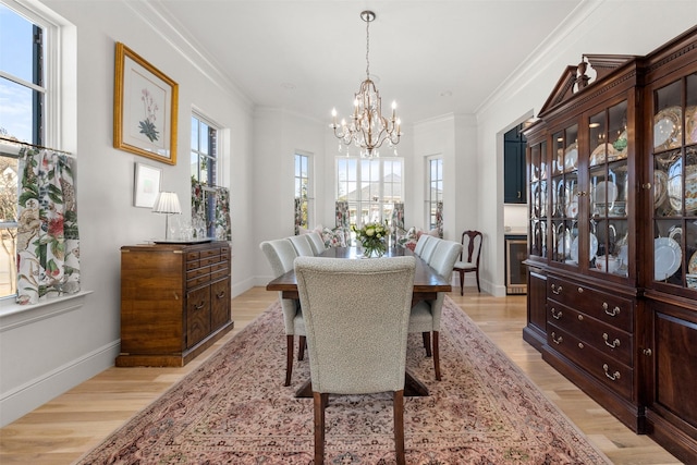 dining area with a notable chandelier, light wood-style flooring, baseboards, and crown molding