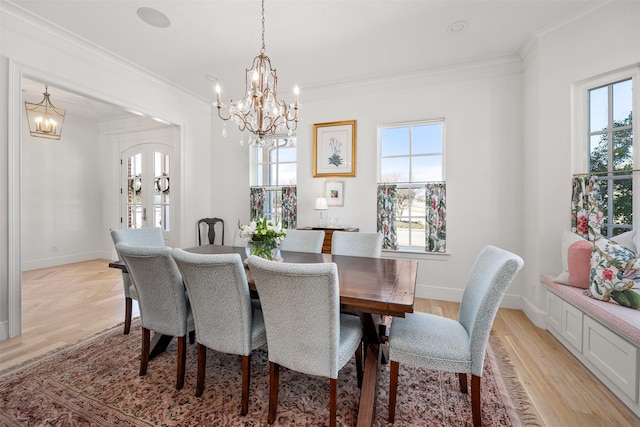 dining space featuring baseboards, ornamental molding, plenty of natural light, and an inviting chandelier