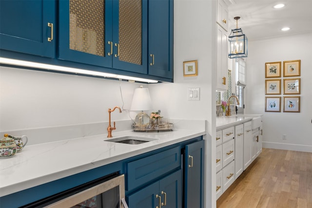 bar featuring baseboards, recessed lighting, a sink, and light wood-style floors