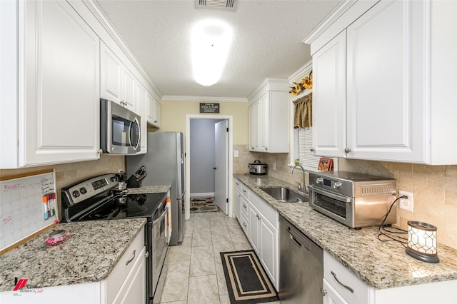 kitchen with stainless steel appliances, white cabinetry, a sink, and tasteful backsplash