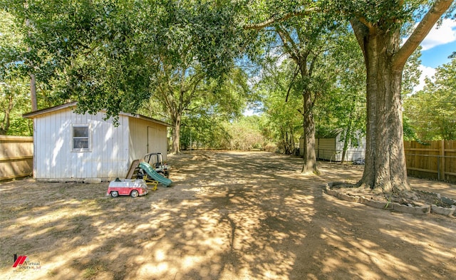 view of yard featuring an outbuilding, a storage shed, and fence