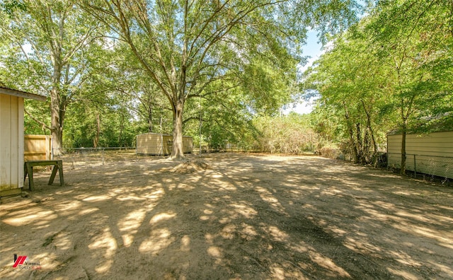 view of yard with a fenced backyard, a shed, and an outbuilding