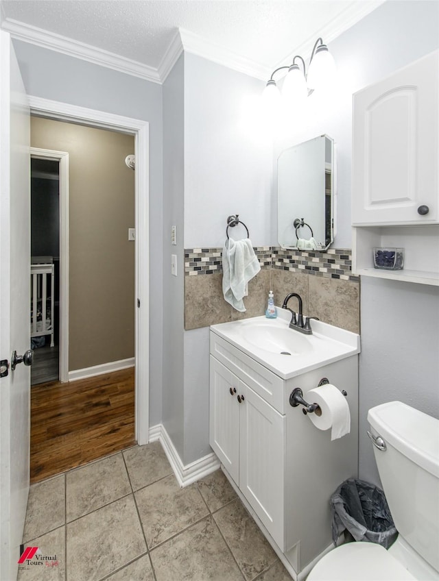 bathroom with toilet, vanity, ornamental molding, tile patterned floors, and tasteful backsplash