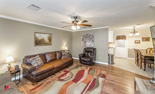 living area with crown molding, a textured ceiling, visible vents, and light wood-style floors