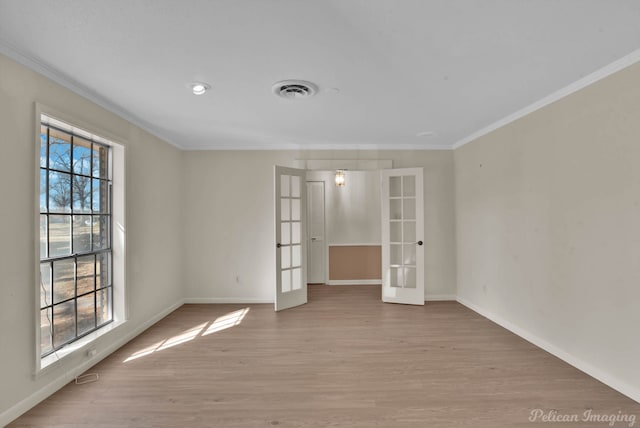 spare room with wood finished floors, visible vents, baseboards, french doors, and crown molding