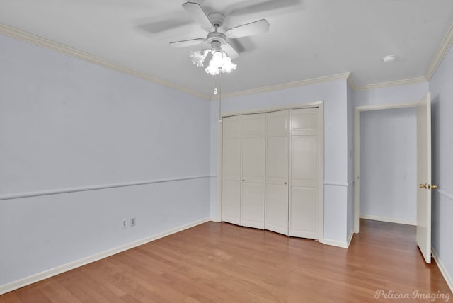 unfurnished bedroom with a ceiling fan, baseboards, wood finished floors, ornamental molding, and a closet