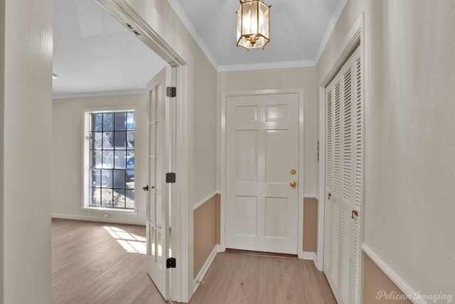 entryway with crown molding, light wood-type flooring, and baseboards